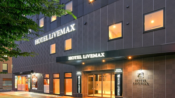 Fachada moderna de un hotel con el nombre 'HOTEL LIVEMAX' visible en letras grandes.