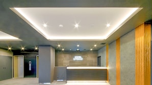 Un vestíbulo moderno con una recepción, ascensores y un cartel que dice "HOTEL LAVEMAX".