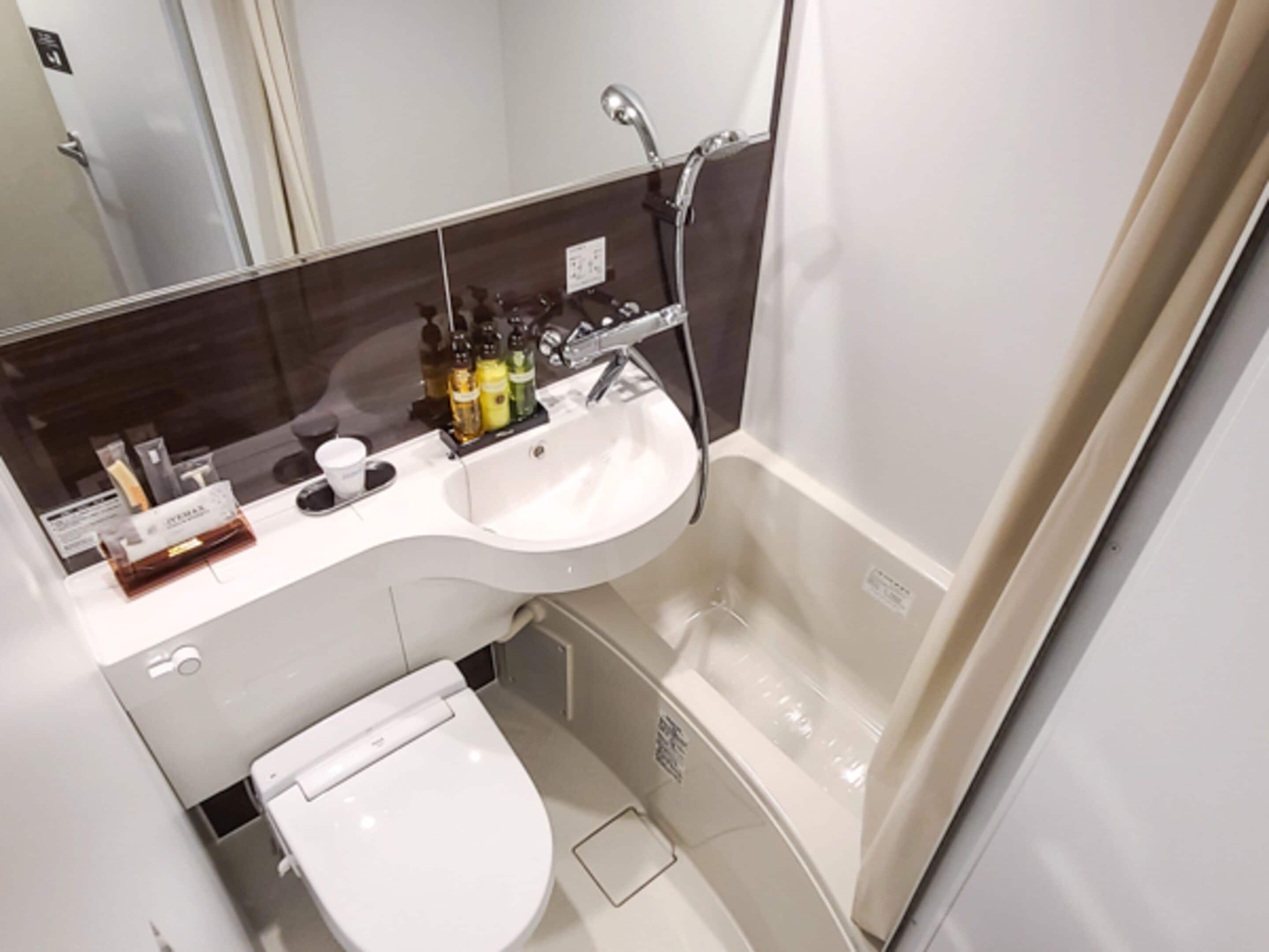 A modern bathroom with a white sink, a toilet, and a shower.
