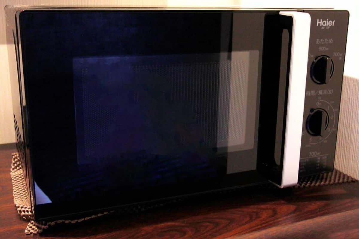 A black and white Haier microwave oven on a wooden surface.