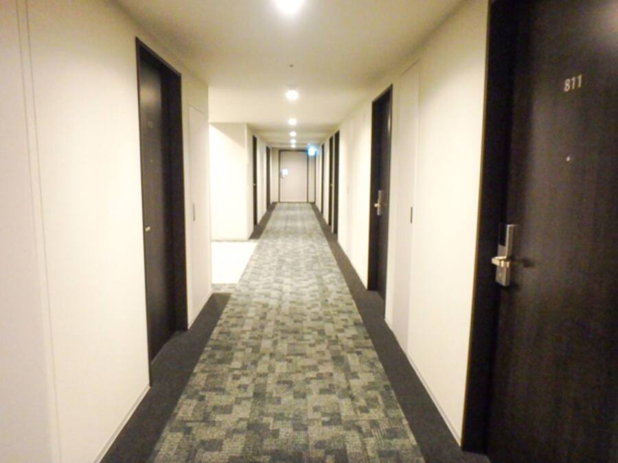 Corredor de hotel com piso carpeteado, portas em ambos os lados e a porta 811 à direita.