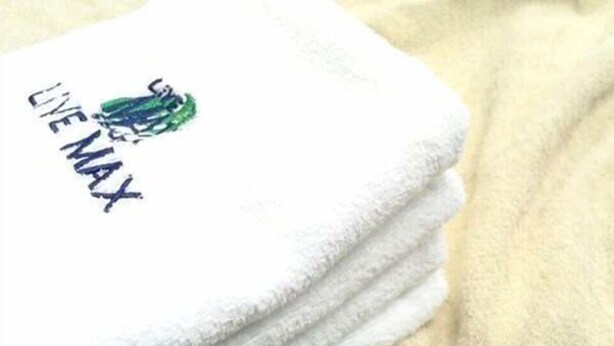 Une pile de serviettes blanches, dont l’une porte un logo et du texte.
