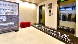 Un hall d’hôtel avec un distributeur automatique, un banc rouge et un comptoir d’accueil.