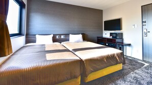 Une chambre d’hôtel avec deux lits, un téléviseur à écran plat, un bureau et une armoire.