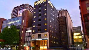 Un hôtel moderne, reconnaissable à son grand panneau lumineux « LIVEMAX », avec de nombreux étages et une entrée bien éclairée.