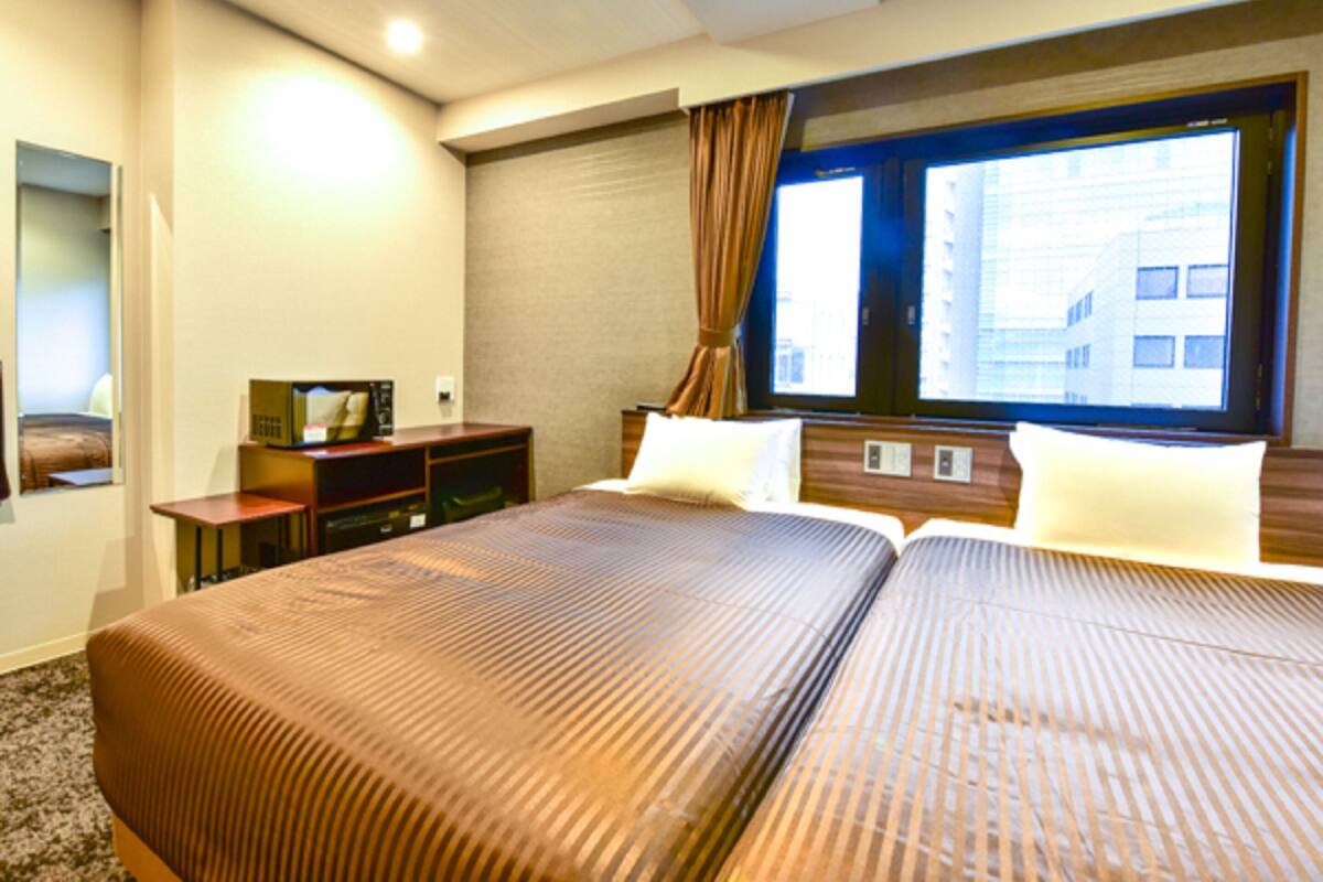 A hotel room with a large bed, a desk, and a window with curtains.