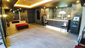 A hotel lobby with a reception desk, seating area, and a LVMH branded machine. - Hotel Livemax Kokura-ekimae (Kitakyushu)