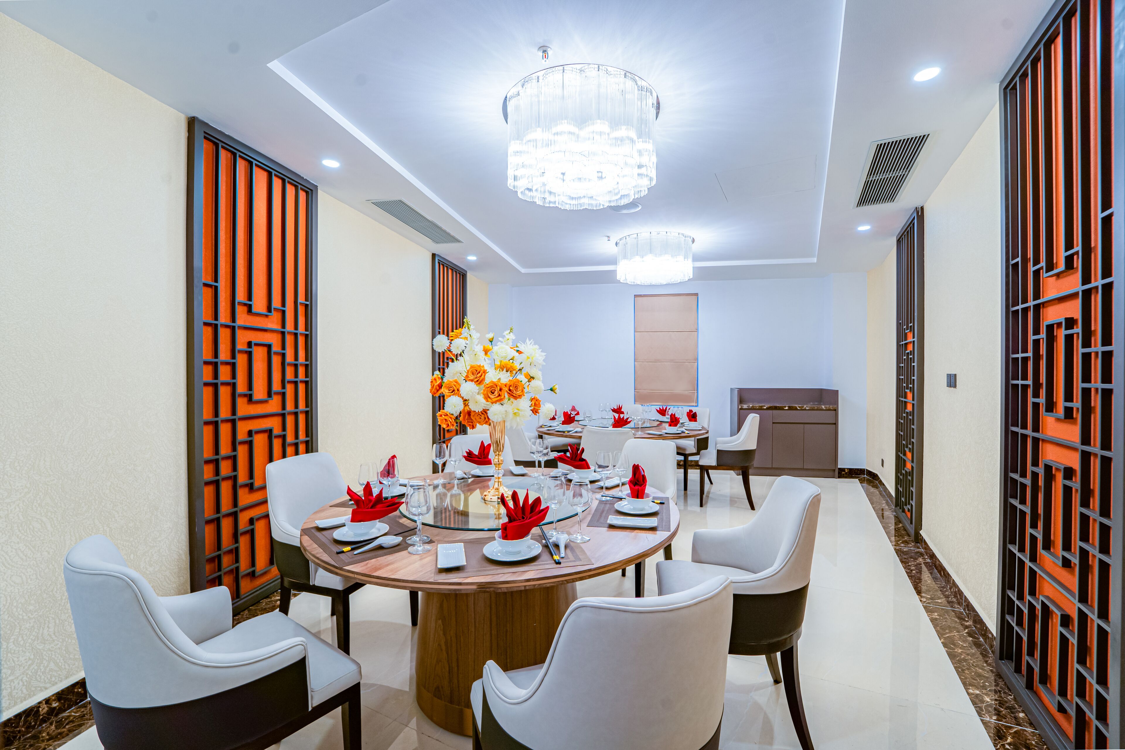 A modern dining area with round tables, white chairs, and a central floral arrangement.