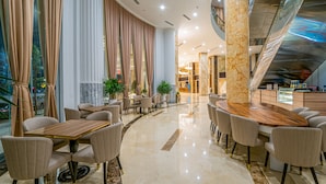 Un vestíbulo de hotel moderno con una recepción de mármol, asientos cómodos y vistas a la ciudad a través de amplios ventanales.