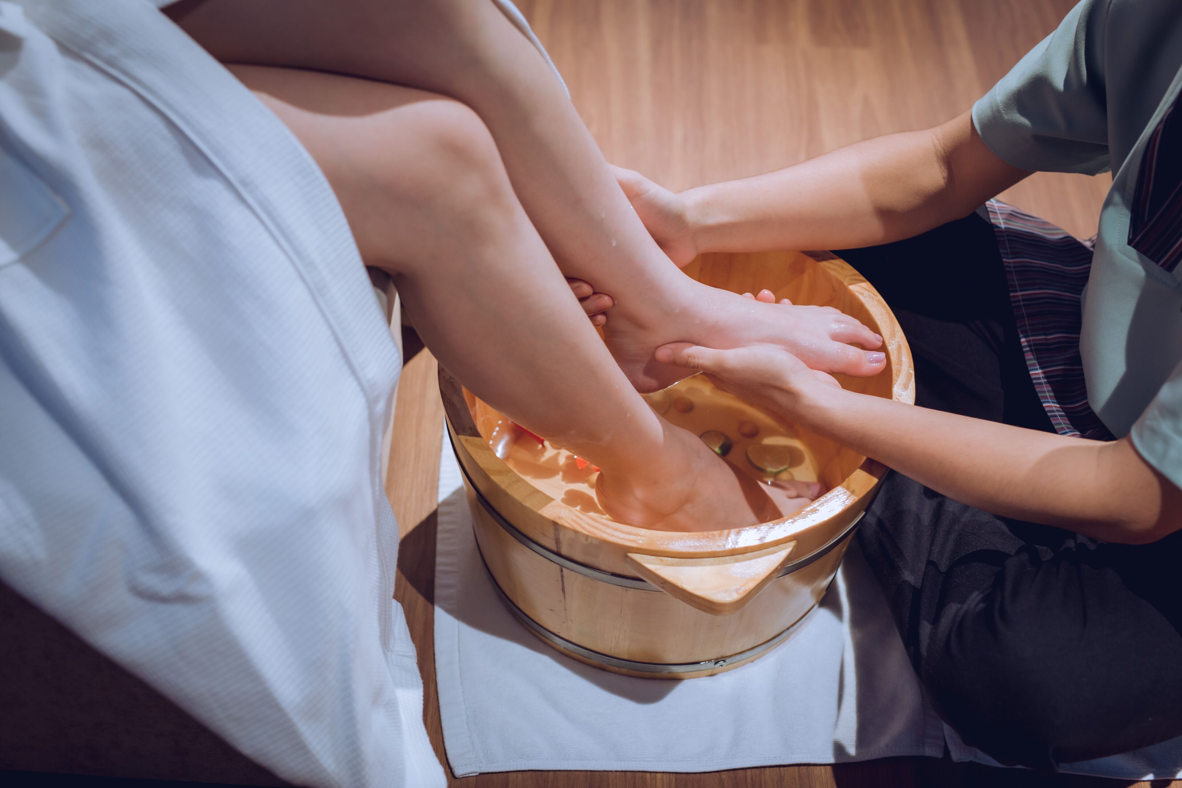 Un bain de pieds dans un récipient en bois, accompagné d'un appareil de massage pour les pieds.