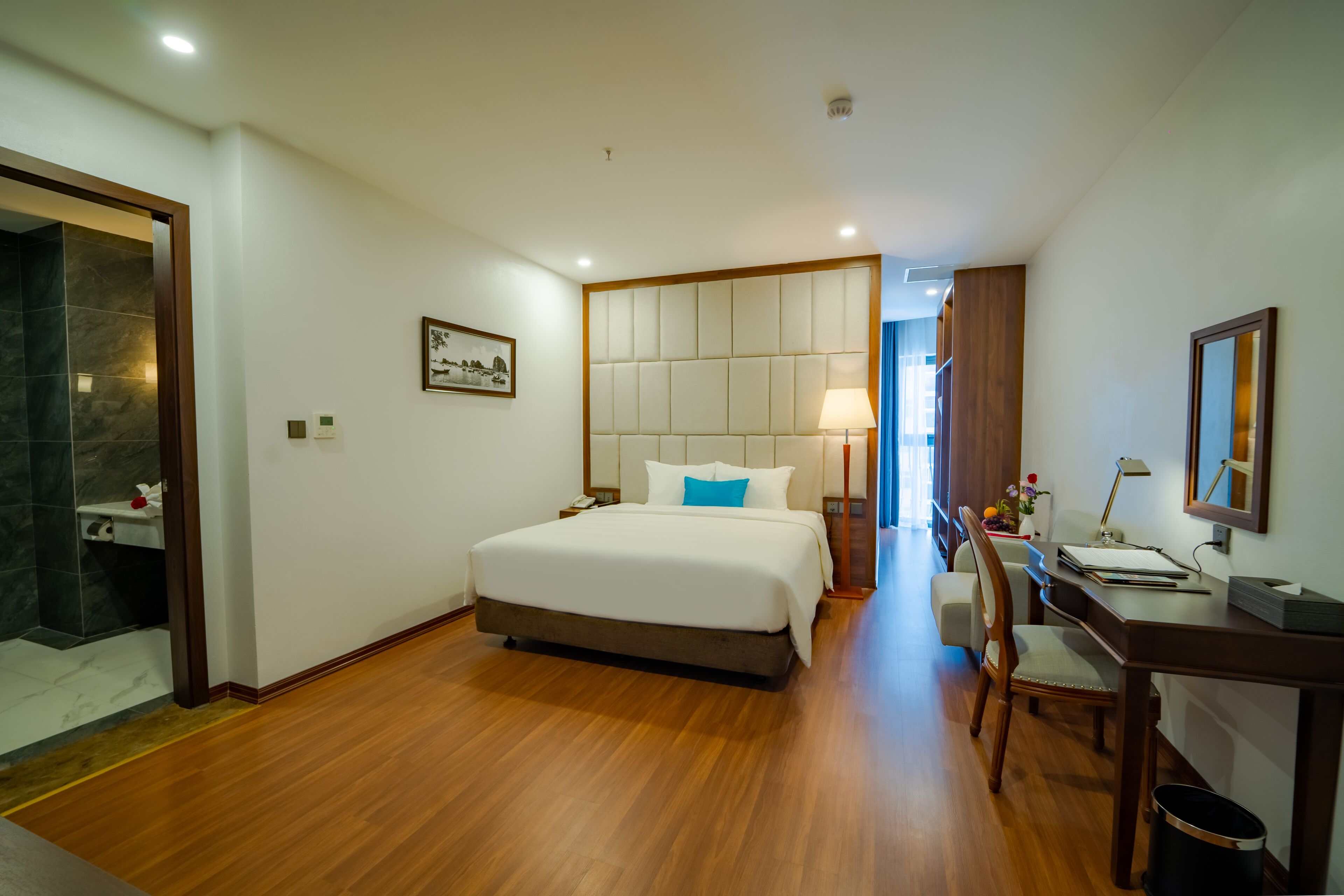 A hotel room with a large bed, a desk, and a chair.