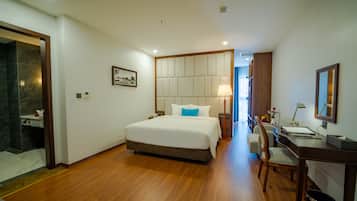 A hotel room with a large bed, a desk, and a chair.