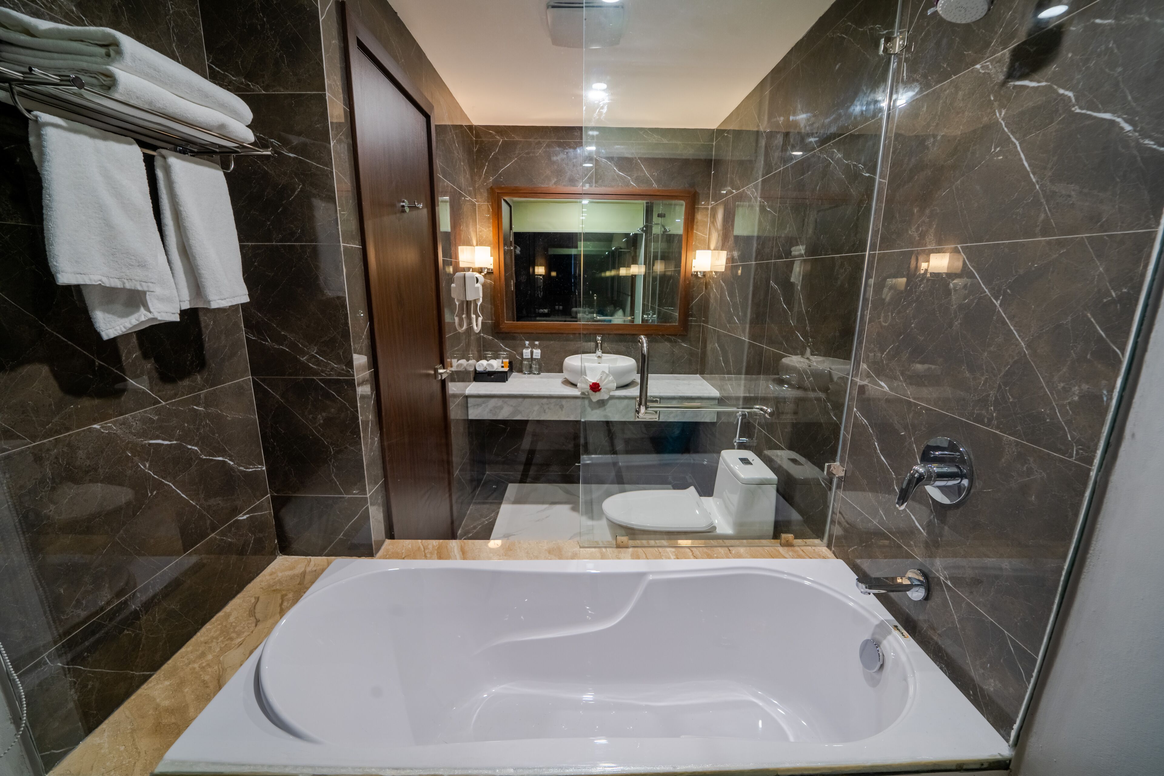 A modern bathroom with a large bathtub, a glass-enclosed shower, and a vanity with a sink and mirror.