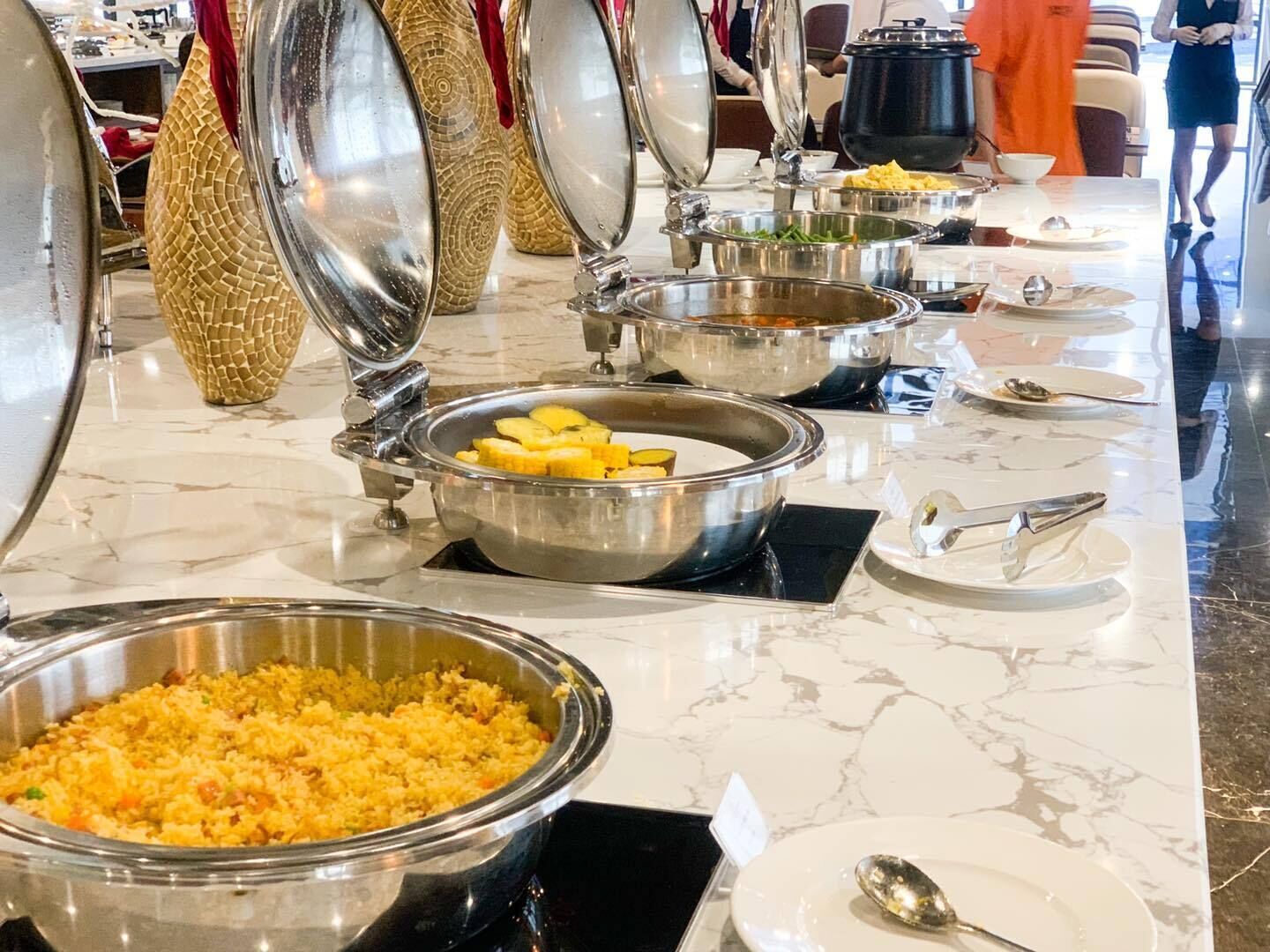 A buffet setup with various food items and utensils on a marble countertop.