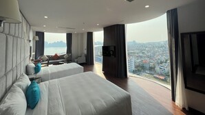 Una habitación de hotel moderna con una cama grande, un sofá, un televisor y vistas a la ciudad.