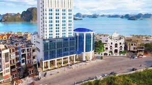 Un hotel moderno con fachada de vidrio central, un edificio destacado con cúpula y vistas al agua.