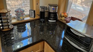 Una cocina con cafetera, jarra de café y taza sobre la encimera.