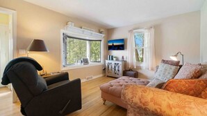 A living room with a sofa, armchair, TV, and windows with blinds. - Beach, harbor & restaurants within walking distance. Family friendly home! (Sturgeon Bay)