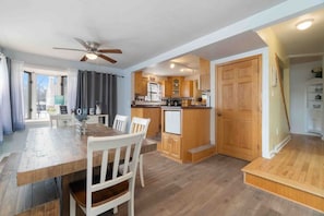 A modern kitchen with wooden cabinets, a built-in oven, and a dining area with a wooden table and white chairs. - Beach, harbor & restaurants within walking distance. Family friendly home! (Sturgeon Bay)