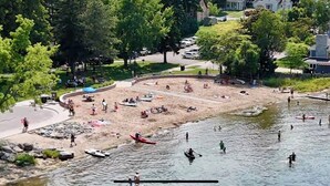 A riverside park with a sandy beach area, boats, and people engaging in water activities. - Beach, harbor & restaurants within walking distance. Family friendly home! (Sturgeon Bay)