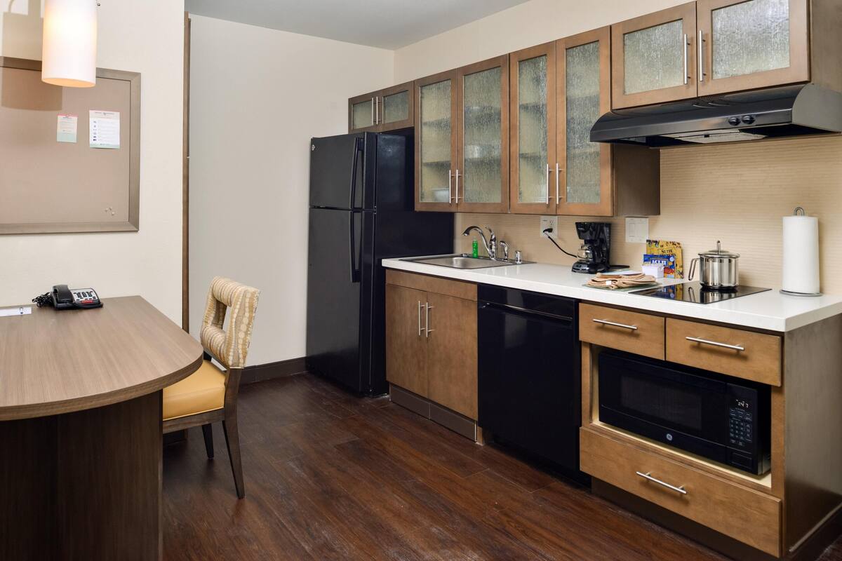 A kitchen with wooden cabinets, a black refrigerator, a microwave, and a coffee maker.