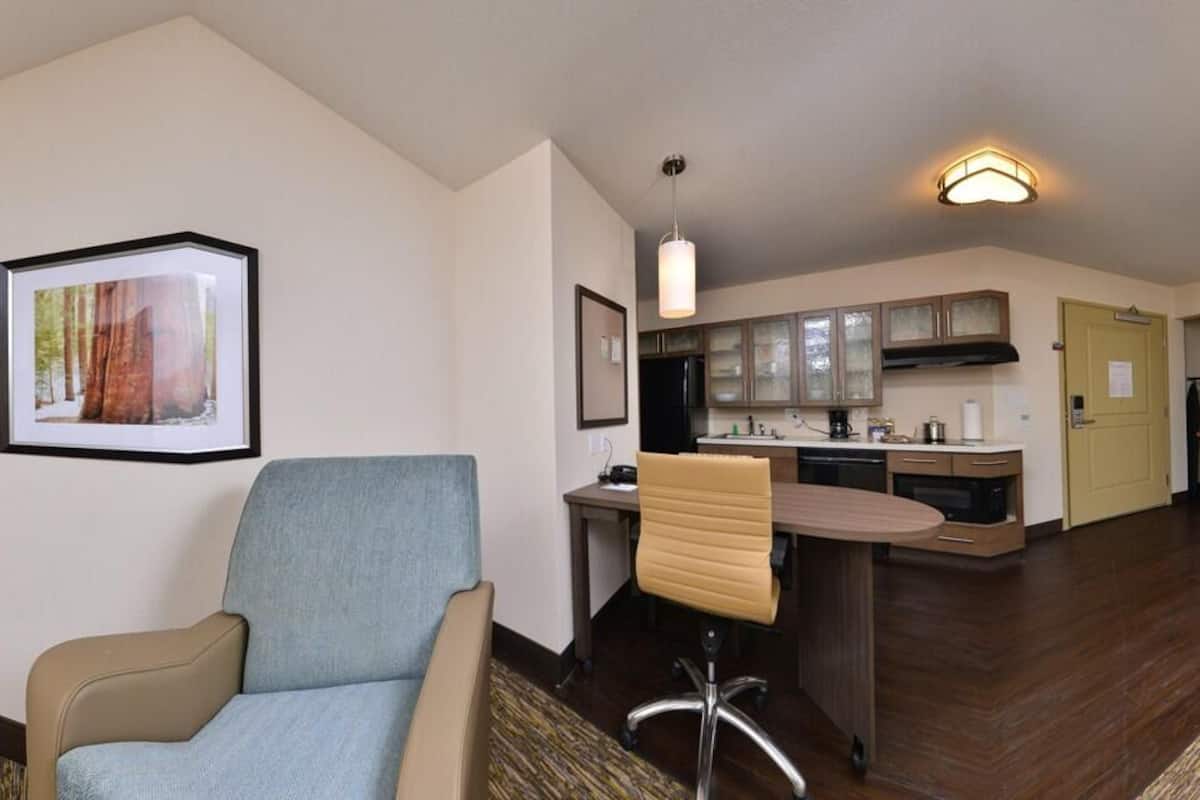 A hotel room with a sofa, a TV, a desk, and a chair.