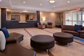 A lobby with a reception desk, seating area, and a glass door entrance. - Candlewood Suites Lodi (Lodi)