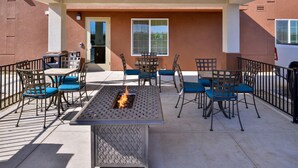 Un patio al aire libre con una chimenea, asientos y vistas del exterior del edificio.