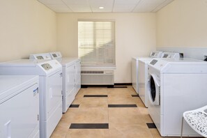 A laundry room with four washing machines and a dryer, a tiled floor, and a window with blinds. - Candlewood Suites Lodi (Lodi)