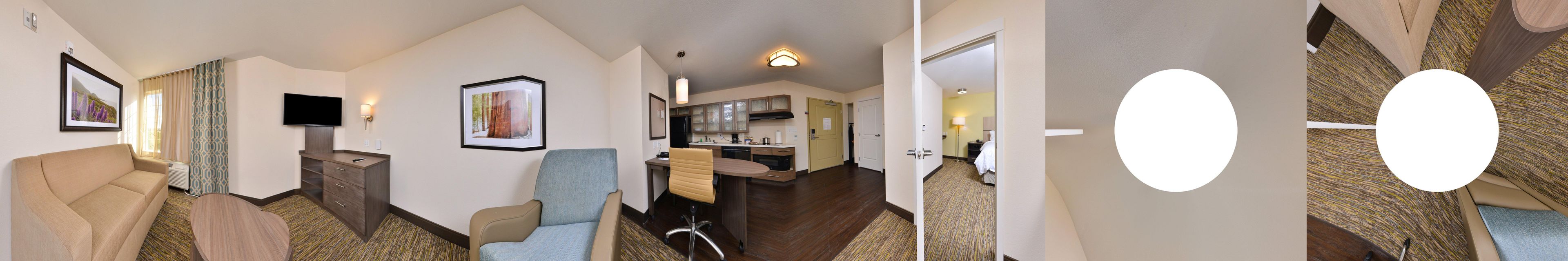 A hotel room with a sofa, a TV, a desk, and a chair.