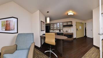 A hotel room with a sofa, a TV, a desk, and a chair.