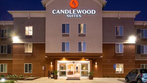 En hotellentrén med modern design, med en tydlig logotyp ovanför namnet, en överbyggd entré och en parkeringsplats framför.