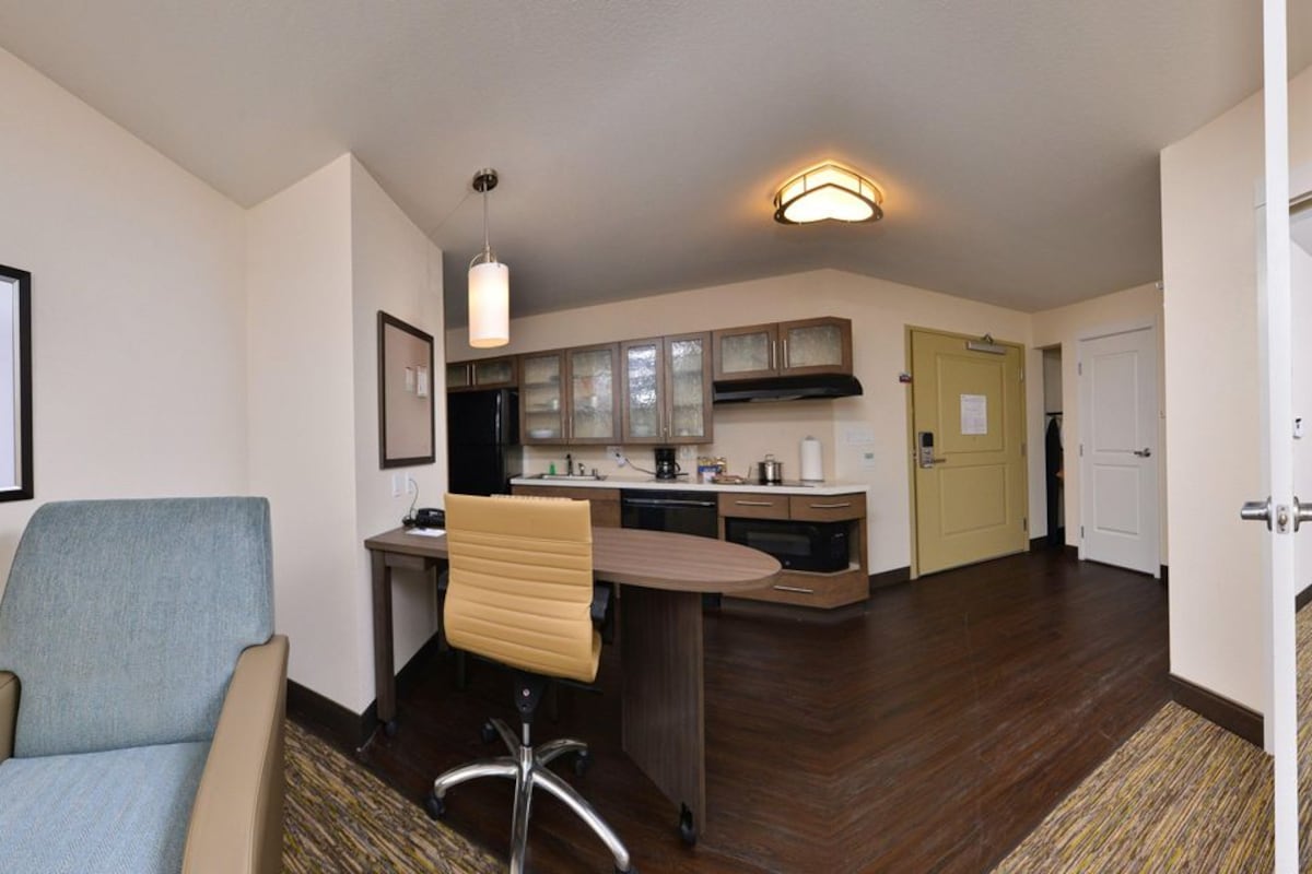 A hotel room with a sofa, a TV, a desk, and a chair.