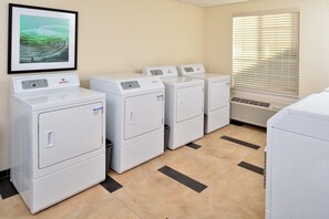 A laundry room with four stacked washers and dryers, a framed picture on the wall, and a window with blinds. - Candlewood Suites Lodi (Lodi)