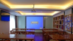 A conference room with a projector screen, wooden tables, and chairs. - Lavande Hotels (Xi'an Xibu Avenue Yangguangcheng) (Xi'an)