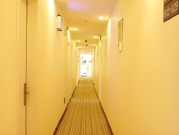 A hotel hallway with a carpeted floor, a door at the end, and a phone number sign on the wall. - 7 Days Inn Chongqing Shapingba High-speed Railway Station (Chongqing)