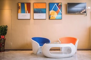 Un espace d’accueil doté de mobilier moderne, de tableaux encadrés accrochés au mur et d’un téléviseur à écran plat.