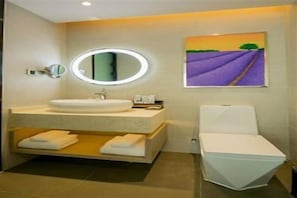 A bathroom with a round mirror, a sink, a toilet, and a painting of lavender fields. - Lavande Hotel (Wuhan)