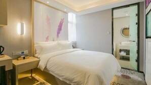 A modern hotel room with a large bed, bedside table, and a bathroom visible through an open door. - Lavande Hotel (Wuhan)