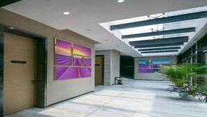A modern hotel lobby with a high ceiling, a skylight, and a large abstract painting on the wall. - Lavande Hotel (Wuhan)