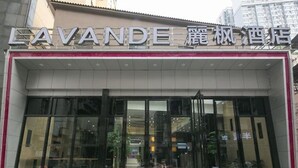 A hotel entrance with a modern facade, large glass doors, and a sign in a foreign language. - Lavande Hotel (Wuhan)
