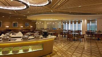 A hotel lobby with a central buffet area, seating arrangements, and a patterned floor.