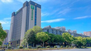 A modern high-rise building with a prominent vertical design, surrounded by lush green trees and a clear blue sky. - Holiday Inn Express Changzhou Xinbei (Changzhou)