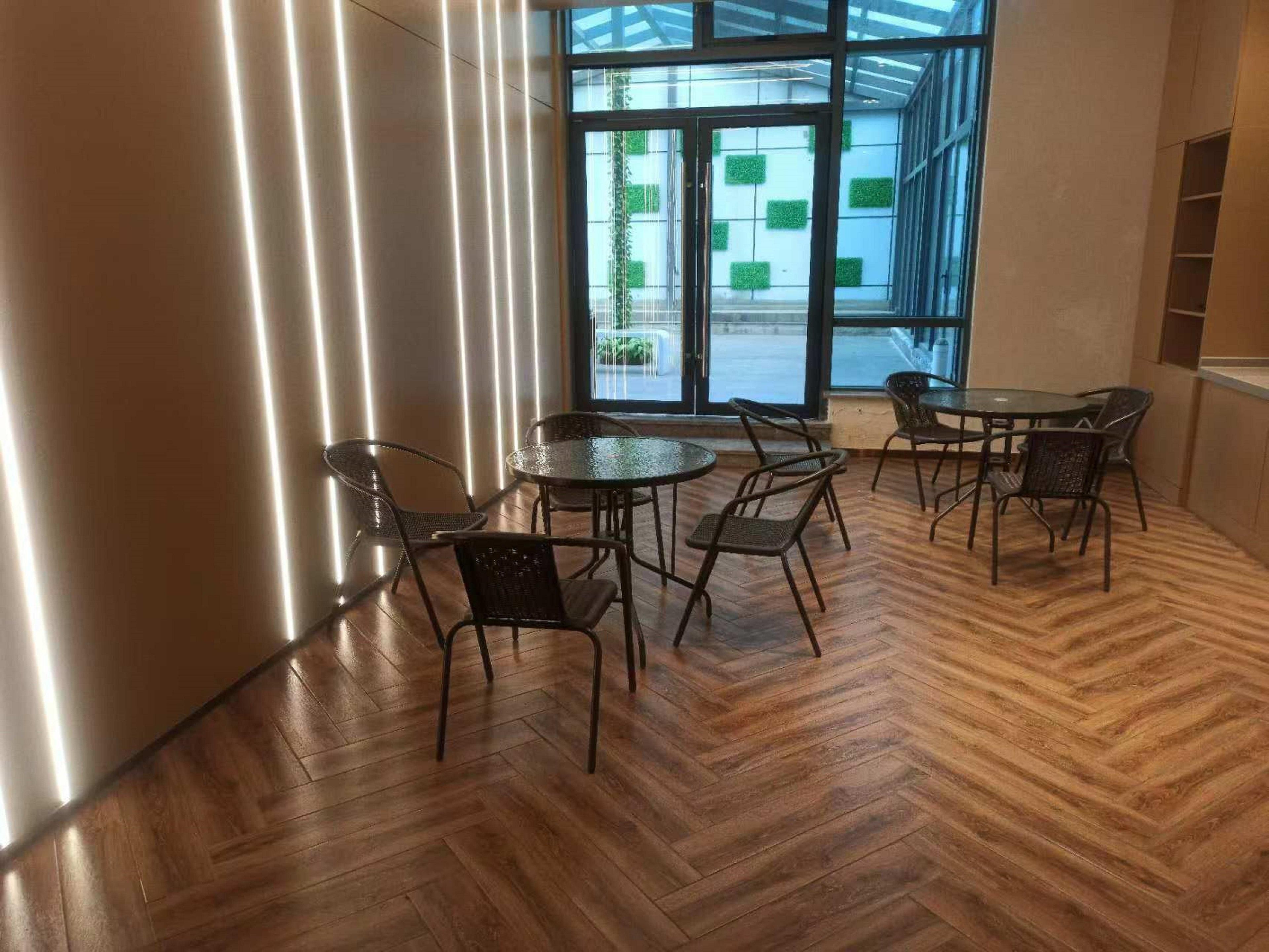 Un interior moderno con piso de madera en espiga, sillas de metal y una mesa de vidrio.