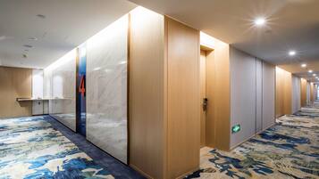 Un pasillo de hotel con pared de mármol, puertas de madera y alfombra estampada.