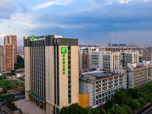 Un hotel moderno de gran altura con un llamativo letrero verde, varios pisos y un diseño arquitectónico contemporáneo.