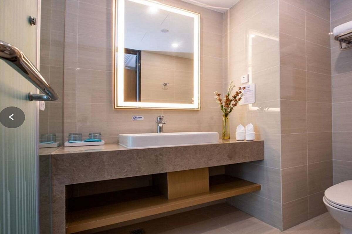 A modern bathroom with a large mirror, a sink, a toilet, and a shower area.