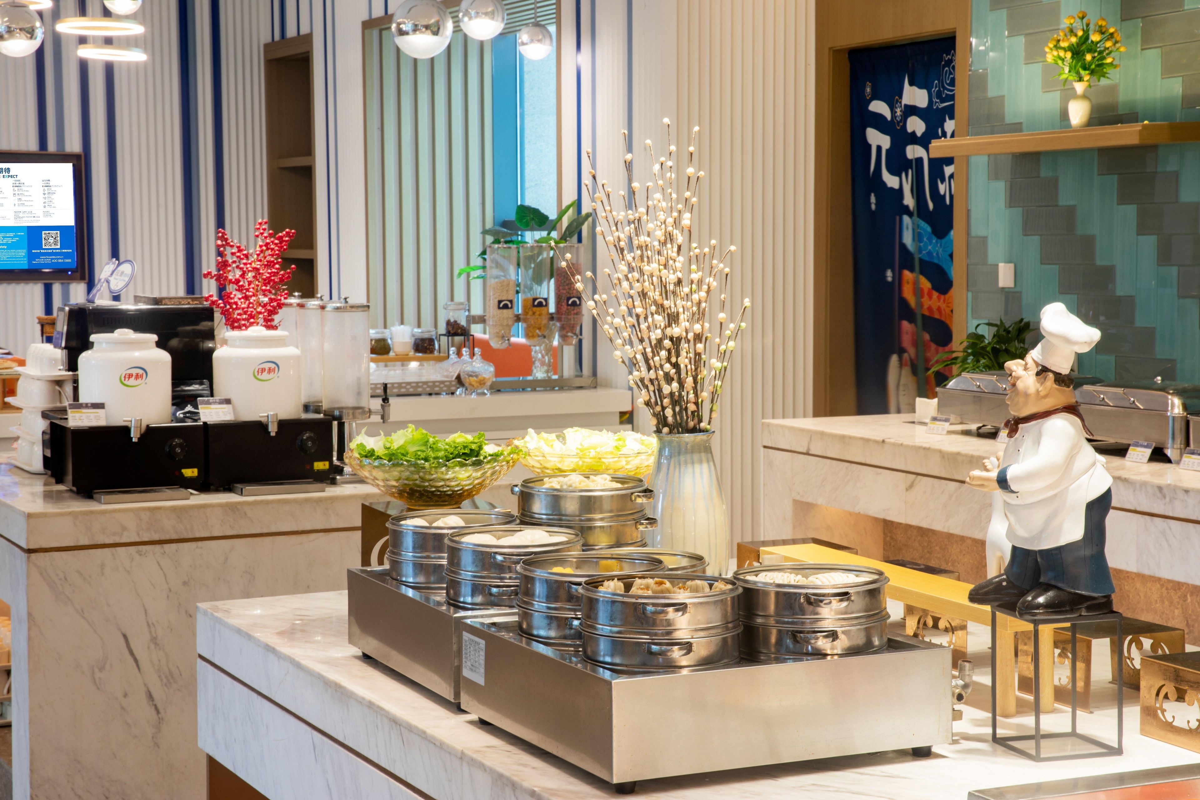 A buffet setup with multiple food containers, a decorative vase, and a chef figurine.