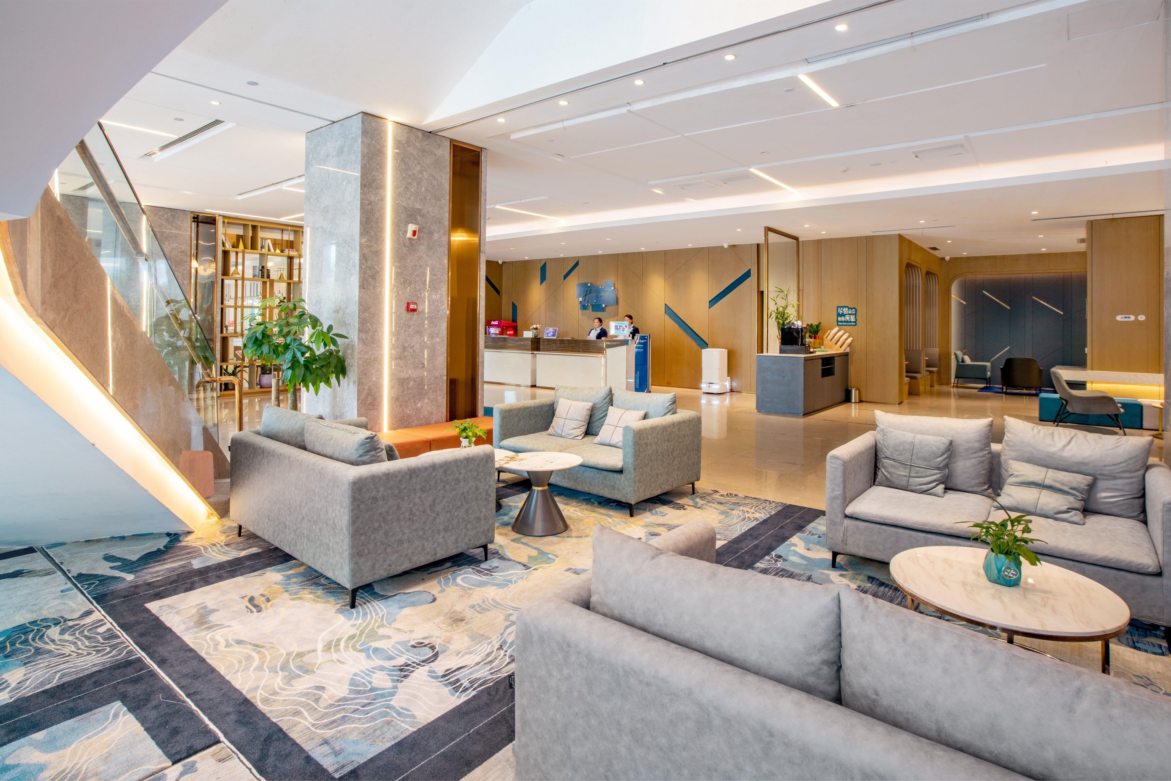 Een moderne lobby met banken, een receptiebalie en een trap.