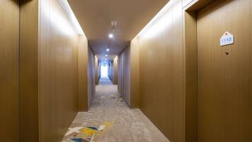 A hotel hallway with wooden walls, a carpeted floor with geometric patterns, and a sign indicating room number 1312.